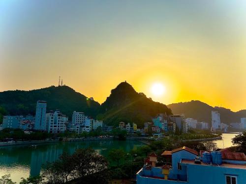 a view of a city with the sun setting behind a mountain at Tung Quang Hotel in Cat Ba