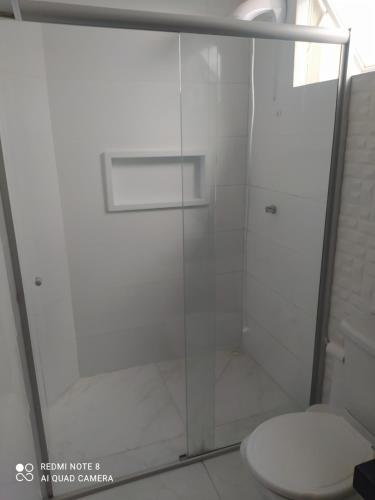 een badkamer met een glazen douche en een toilet bij Flat central dois quartos in Guaporé