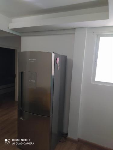 een roestvrijstalen koelkast in een kamer met een raam bij Flat central dois quartos in Guaporé