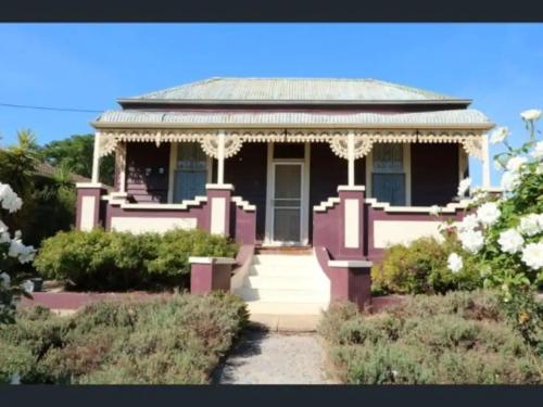 a small purple house with a porch in a garden at R&R Blue Diamond Luxury Cottage Maryborough, Vic in Maryborough