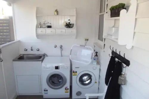 a small kitchen with a washing machine and a sink at R&R Blue Diamond Luxury Cottage Maryborough, Vic in Maryborough