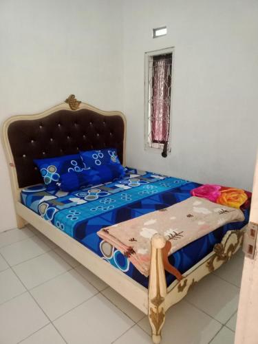 um quarto com uma cama com lençóis azuis e almofadas azuis em Mutiara Dieng em Wonosobo
