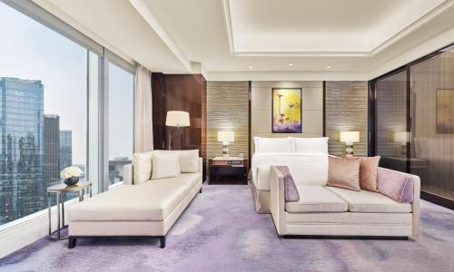 a hotel room with a bed and a couch and windows at Fairmont Chengdu in Chengdu
