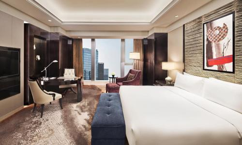 a hotel room with a large bed and a desk at Fairmont Chengdu in Chengdu