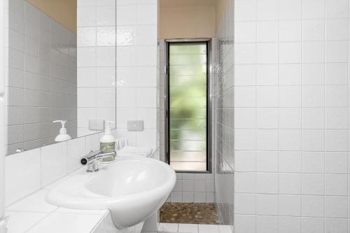 a white bathroom with a sink and a mirror at Above The Pass in Byron Bay