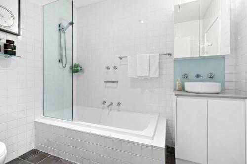 a white bathroom with a tub and a sink at 'Collins Central' Sleek Light-filled Pad in the CBD in Melbourne
