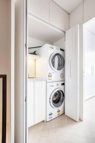 a white laundry room with a washer and dryer at 'The Fern' Split-Level Retreat with Lush Courtyard in Sydney