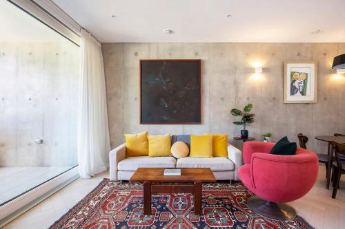 a living room with a white couch and a red chair at 'The Fern' Light-Filled Urban Retreat near Dining in Sydney