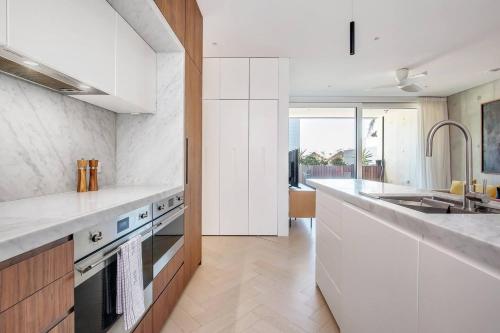 a kitchen with white cabinets and a sink and a stove at 'The Fern' Light-Filled Urban Retreat near Dining in Sydney