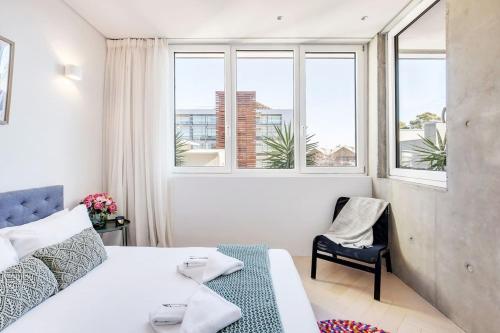 a bedroom with a bed and a chair and windows at 'The Fern' Light-Filled Urban Retreat near Dining in Sydney