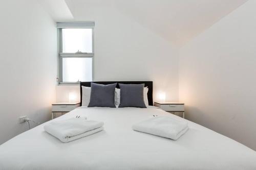 a bedroom with a large white bed with two pillows at Urban Oasis Custom Made for Cosmopolitan Living in Sydney