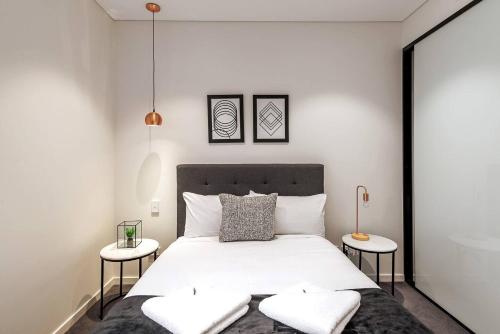 a bedroom with a large white bed with two tables at Sunny Courtyard Escape in Sydney's Little Italy in Sydney