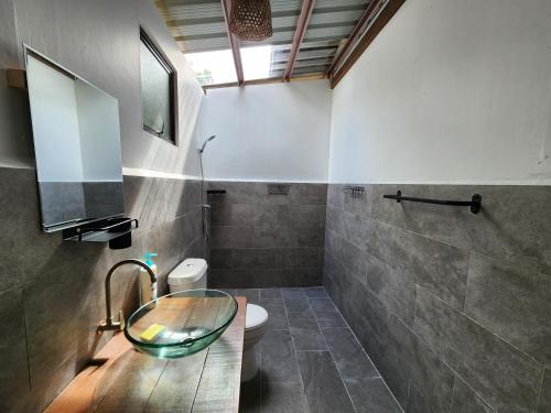 uma casa de banho com um lavatório de vidro e um WC. em Bigfin beach resort em Kota Belud