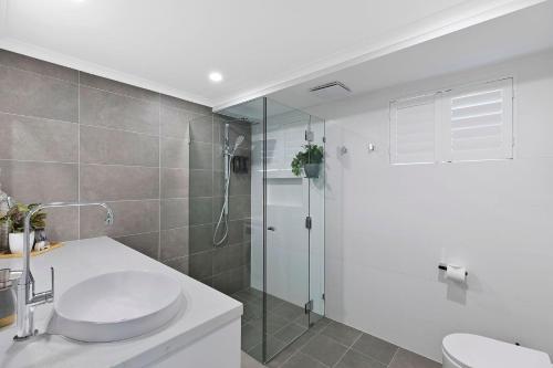 biała łazienka z umywalką i prysznicem w obiekcie Ocean Pines Apartment 5 w mieście The Entrance