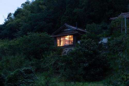 ein Haus mit einem Licht im Fenster in der Unterkunft Ryokuinsansou-bettei - Vacation STAY 48641v in Yasugi