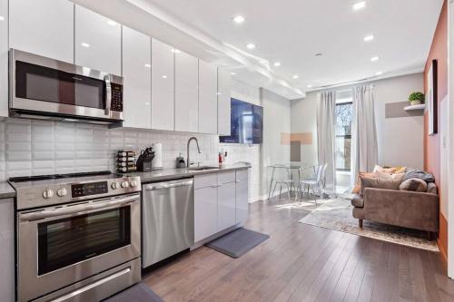 uma cozinha com electrodomésticos de aço inoxidável e uma sala de estar em SWJ 4th and 5th - Save on 2Day+ Stays_Duplex em Nova York