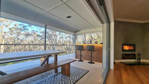 Un comedor con una mesa y un gran ventanal. en Blue Mountains Sweet Retreat, en Leura