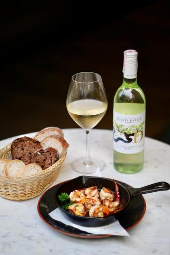 a glass of white wine and a plate of food and bread at BYD Lofts - Boutique Hotel & Serviced Apartments - Patong Beach, Phuket in Patong Beach