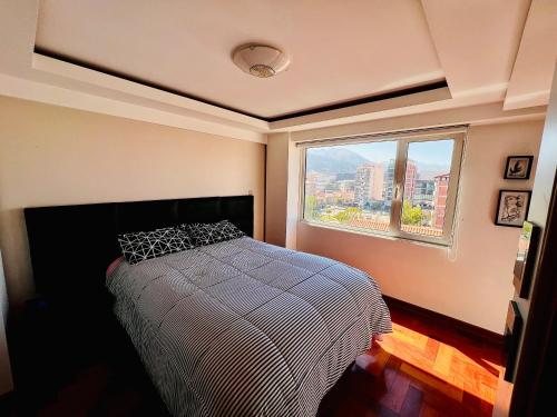 a bedroom with a bed and a large window at Departamento La Terraza in Cusco