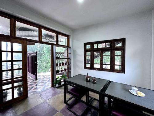 a dining room with a black table and windows at Syengden Nikunj in Darjeeling