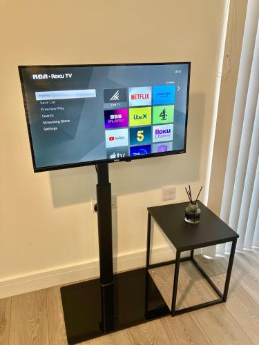 a flat screen tv on a stand next to a table at Modern Studio for LONG STAY BUSINESS & RELOCATIONS in Hemel Hempstead