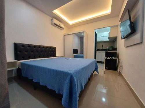 a bedroom with a blue bed and a flat screen tv at Loft em Olaria in Rio de Janeiro