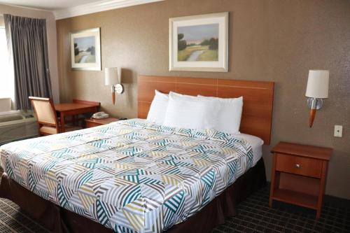 Motel 6-Alvin, TX في ألفين: غرفة فندق مع سرير مع لحاف ملون