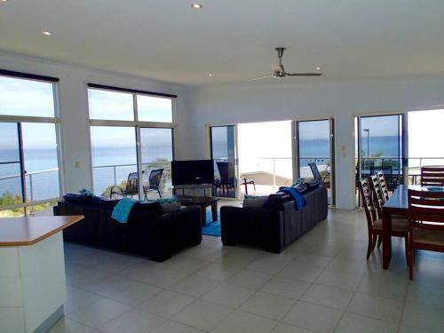 a living room with couches and a table and chairs at Blue Ocean View Beach House, Tangalooma Resort in Tangalooma