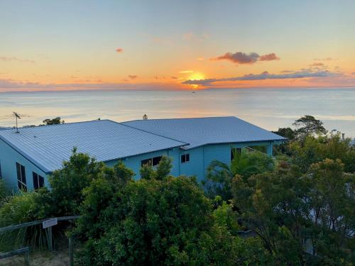a house on a hill with the sunset in the background at Blue Ocean View Beach House, Tangalooma Resort in Tangalooma