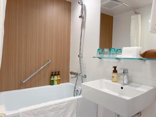 a bathroom with a sink and a tub and a toilet at Hotel Mystays Nagoya Nishiki in Nagoya