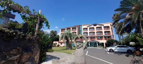 a building with a statue in front of a parking lot at The Bay Jeju Resort in Seogwipo