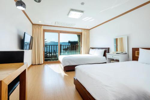 a hotel room with two beds and a balcony at The Bay Jeju Resort in Seogwipo