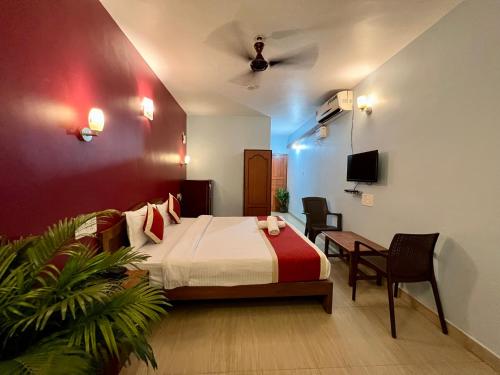 a bedroom with a bed and a table and a tv at Baga Beach Myron in Baga