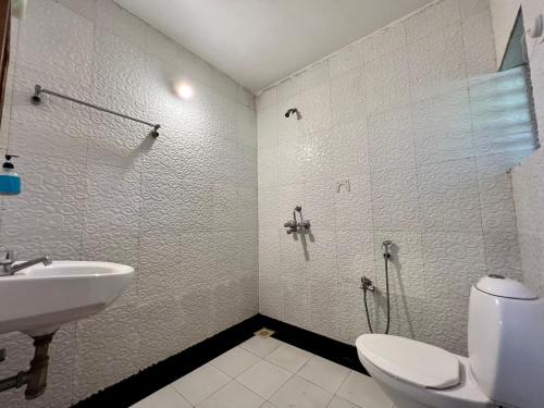 La salle de bains est pourvue d'un lavabo, de toilettes et d'une douche. dans l'établissement Baga Beach Myron, à Baga