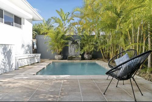 una piscina con 2 sillas junto a una casa en Byron Bay Holiday Homes - Marie and Fred's Villa, en Byron Bay
