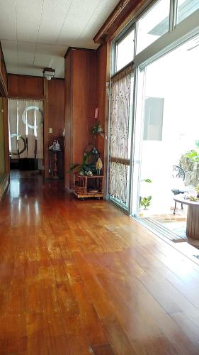 an empty room with a wooden floor and large windows at フェーヌカジ洋室 in Miyako Island