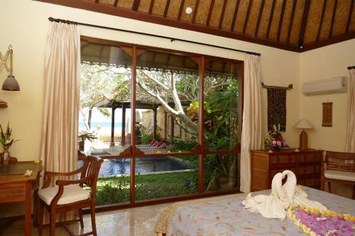 a bedroom with a large window with a view of a pool at Nusa Indah Candidasa in Candidasa