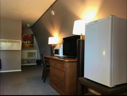 a room with a desk with a microwave and a tv at The little chalet motel in Brandon