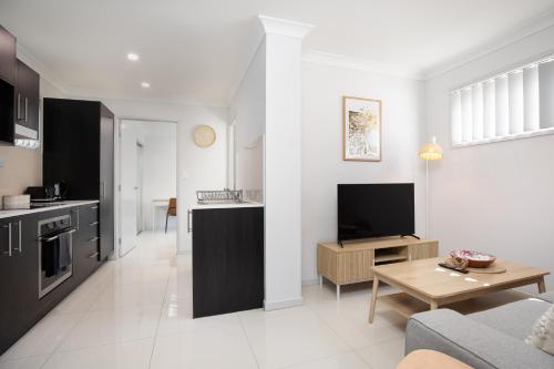 a kitchen and living room with a couch and a table at Neatly Presented,Air Con and Modern! in Brisbane