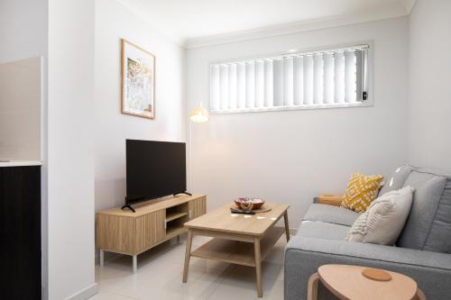 a living room with a blue couch and a tv at Neatly Presented,Air Con and Modern! in Brisbane