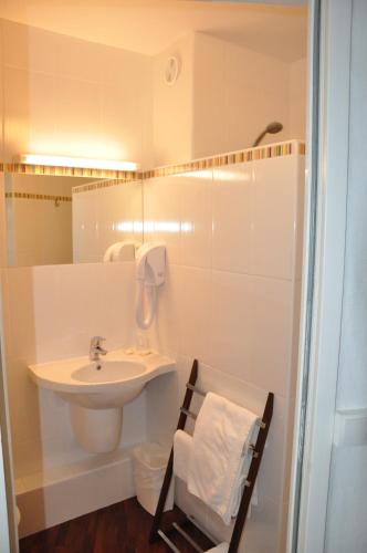 a white bathroom with a sink and a mirror at The Originals City, Hôtel du Château, Pontivy in Pontivy