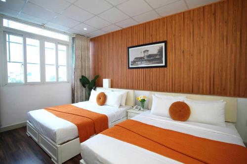 ホーチミン・シティにあるSaigon Central Hotelのオレンジと白のベッドが2つあるホテルの部屋