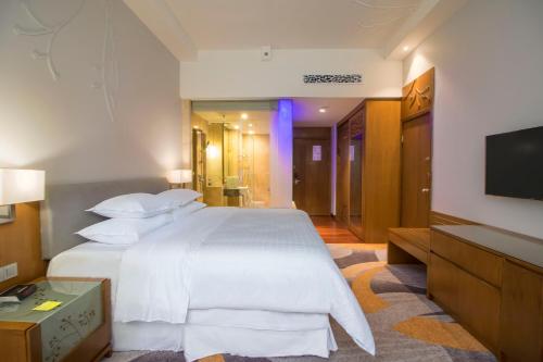 a bedroom with a white bed and a flat screen tv at Four Points by Sheraton Manado in Manado