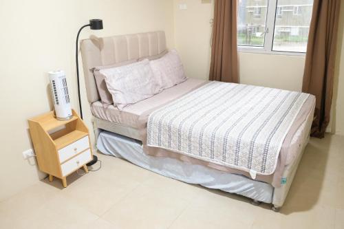 a bedroom with a bed with a night stand and a window at Spacious 1BR Corner Unit in IT Park in Cebu City
