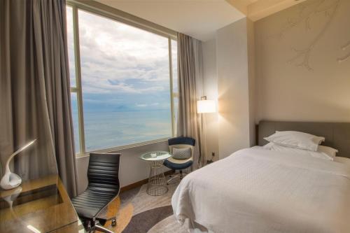 a hotel room with a bed and a large window at Four Points by Sheraton Manado in Manado