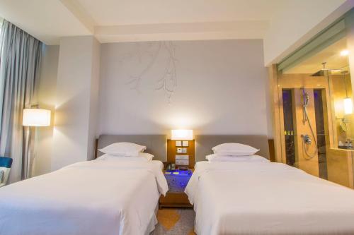 two beds in a hotel room with two lamps at Four Points by Sheraton Manado in Manado