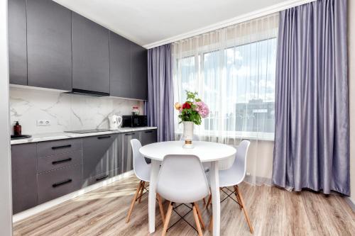 una cocina con mesa y sillas y un jarrón de flores en Новая квартира в самом центре города en Astaná