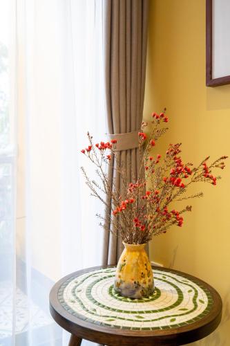 a vase sitting on a table with flowers in it at Hoianan Boutique Hotel in Hoi An