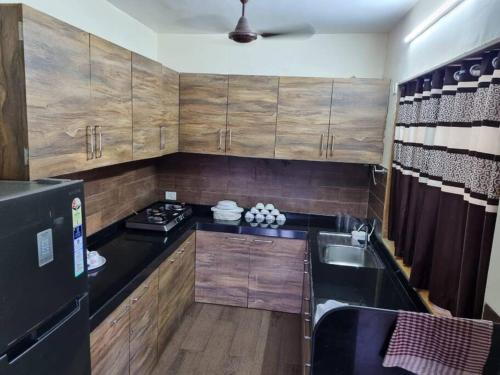 a small kitchen with wooden cabinets and a black refrigerator at Slice Of Heaven.3-Bedroom Villa with Pool & Gazebo in Lonavala