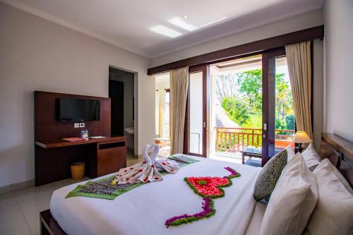 a hotel room with a bed with flowers on it at Lili Cottage Ubud in Ubud